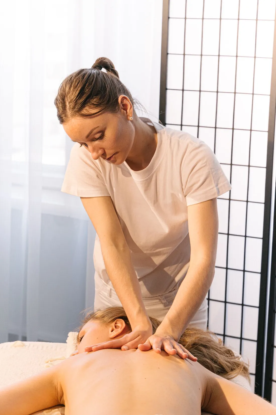 Masaje corporal profundo realizado por una terapeuta en una sala serena de spa